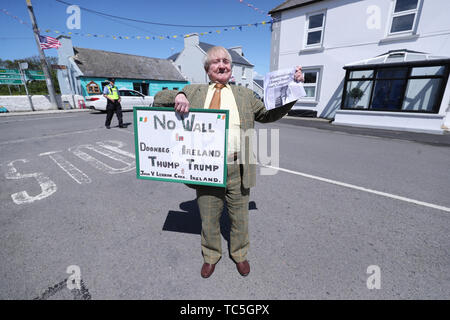 Anti Donald Trump Protestor John Lennon holds up a sign in the village of Doonbeg in Co Clare as a huge security operation swings into operation for the arrival of the US President. Stock Photo