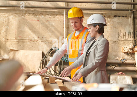 Waist up portrait of female production manager discussing plans standing in indusrial workshop Stock Photo