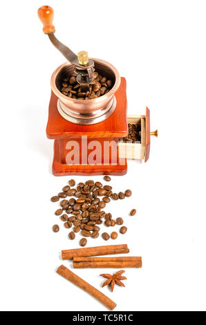 Coffee grinder with coffee beans and spices and spices cinnamon sticks, star anise on white background. Stock Photo