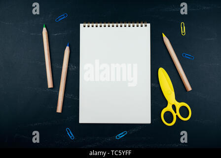 Different school supplies on black chalkboard background. Back to school background. Flat lay, copy space. Stock Photo