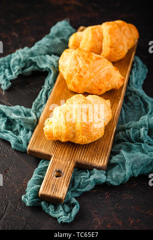 Tasty freshly baked croissants on wooden cutting board, top view Stock Photo