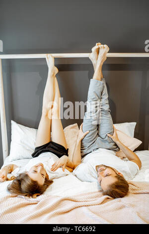 Young couple lying together on the bed, relaxing and having fun in the bedroom at home Stock Photo
