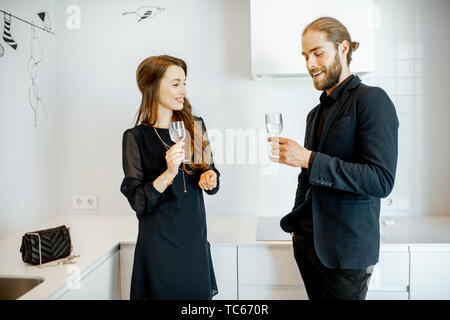 Man and woman in black formal clothes having unofficial meeting with drinks in the kitchen at home Stock Photo