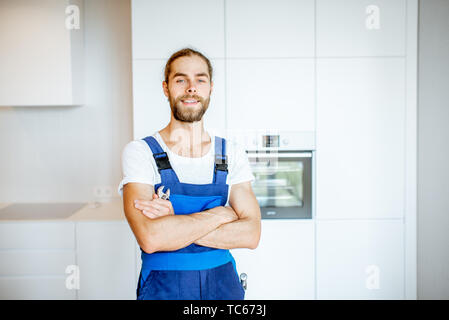 Portrait of a handyman in uniform standing in the renovated kitchen at home Stock Photo