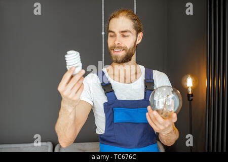 Handyman choosing between energy saving and traditional lightbulb at home Stock Photo