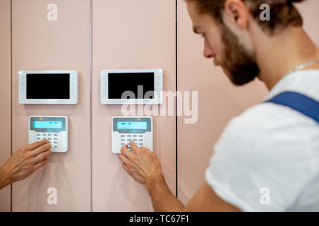Workman setting up the alarm with keyboard near the entrance at home Stock Photo