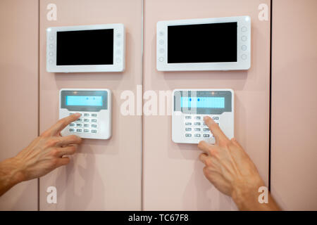 Workman setting up the alarm with keyboard near the entrance at home, close-up Stock Photo