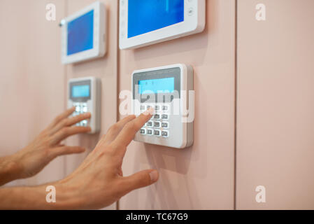 Workman setting up the alarm with keyboard near the entrance at home, close-up Stock Photo