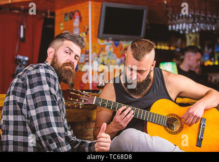 Live music concert. Acoustic performance in pub. Hipster brutal bearded with friend in pub. Cheerful friends sing song guitar music. Relaxation in pub. Stock Photo