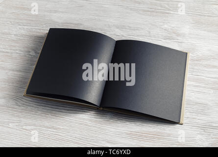 Opened blank black brochure on light wood table background. Stock Photo