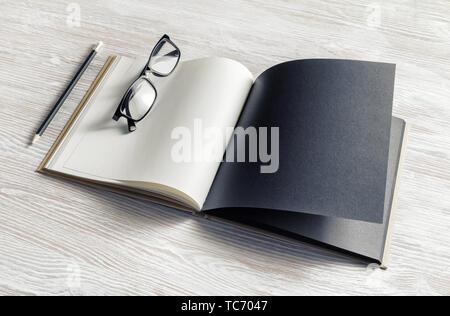 Mockup of opened blank booklet, pencil and glasses on light wooden background. Stock Photo