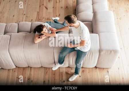 overhead view of couple sitting on sofa and looking at each other