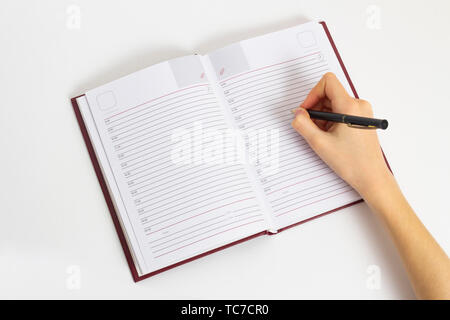 Hand with pen is ready to write in an open notebook. Opened notebook with hand with black pen Stock Photo