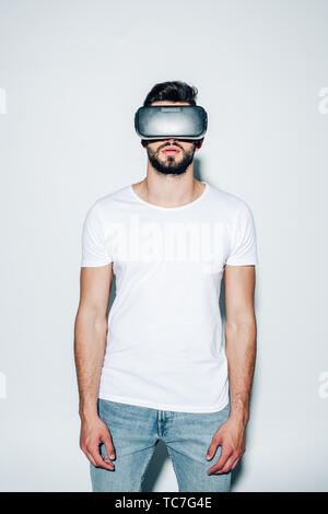 bearded man wearing virtual reality headset while standing on white Stock Photo