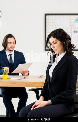 selective focus of upset woman sitting near handsome recruiter Stock Photo