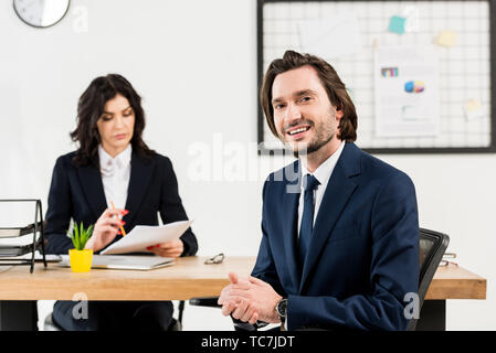 selective focus of cheerful man looking at camera near attractive recruiter Stock Photo