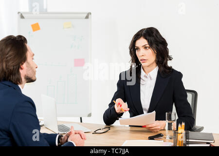 selective focus of attractive recruiter holding documents and looking at employee Stock Photo