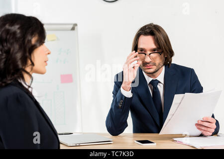 selective focus of recruiter touching glasses while looking at attractive woman Stock Photo