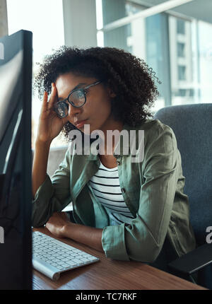 Worried young businesswoman looking at computer Stock Photo