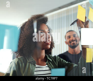 Office colleagues writing business ideas and plans on sticky not Stock Photo