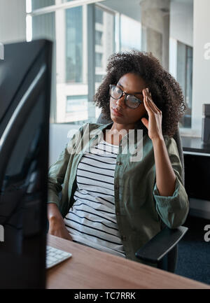 Tired overworked businesswoman looking at computer in an office Stock Photo