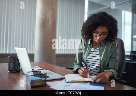 Businesswoman writing in an agenda on a desk at office Stock Photo