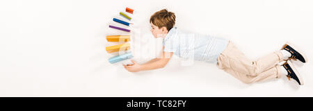 panoramic shot of cute kid holding colorful books while flying on white Stock Photo