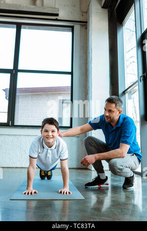 father helping son with plank exercise at sports center Stock Photo