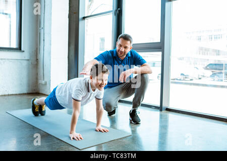 father helping son with push up exercise at gym with copy space Stock Photo