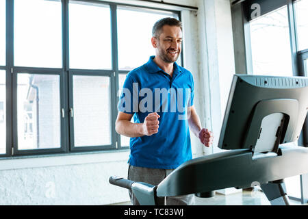 handsome smiling man training on treadmill at gym with copy space Stock Photo