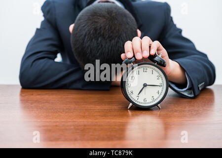 A tired young man holds the alarm clock Stock Photo