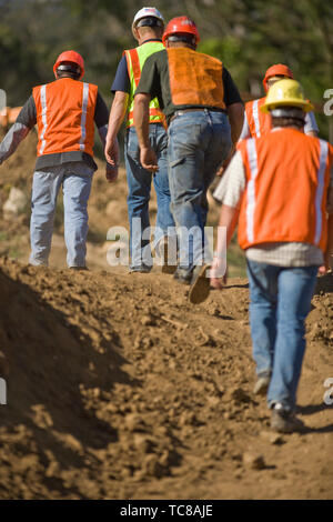 Group of construction workers in safety gear walking on a construction site. Stock Photo