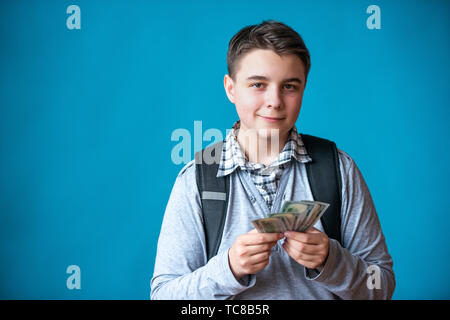 Cash loan, first easy money and spending money. The boy teenager holds in the hands the earned money. Earnings or winnings online. Stock Photo