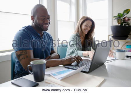 Happy couple paying bills at laptop
