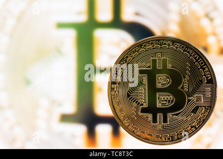Golden color bitcoin on a blurred bitcoin symbol background Stock Photo