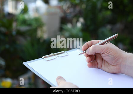 Human Hand Writing on Clipboard with White Paper Stock Photo