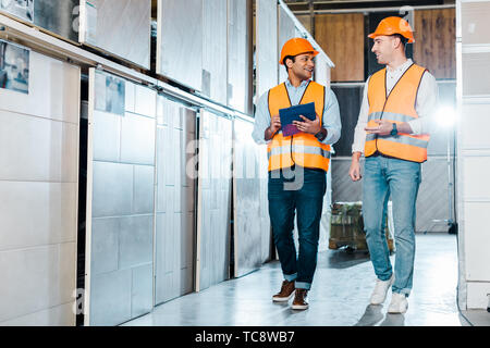 cheerful multicultural warehouse workers talking in tiles department Stock Photo