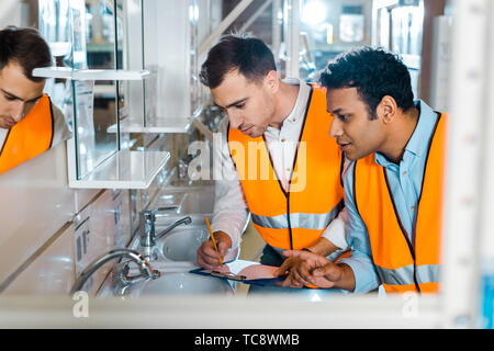 selective focus of attentive multicultural colleagues working in plumbing department Stock Photo
