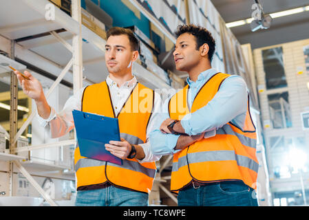 attentive multicultural warehouse workers in safety vests working in plumbing department Stock Photo