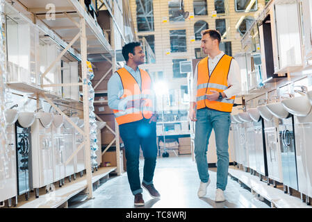 smiling multicultural warehouse workers talking in plumbing department Stock Photo