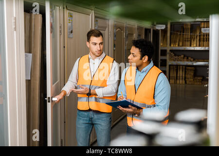selective focus of handsome worker opening door near indian colleague Stock Photo