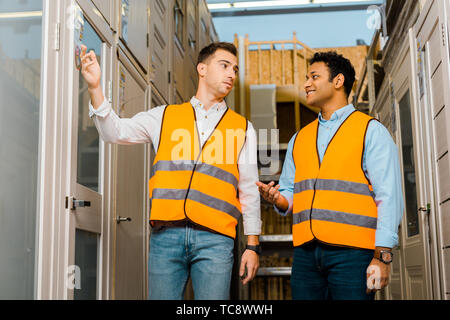 multicultural warehouse workers talking while standing in doors department Stock Photo