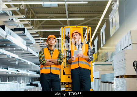 selective focus of serious multicultural workers standing near scissor lift Stock Photo