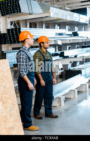 two serious multicultural friends in uniform standing in warehouse Stock Photo