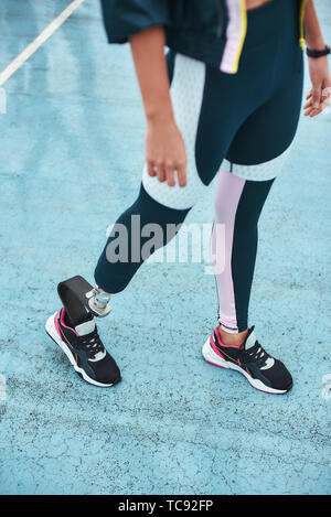 Just keep running. Cropped image of disabled woman in sportswear with bionic leg standing on stadium while doing her morning workout. Sport concept. Disabled Sportsman Stock Photo