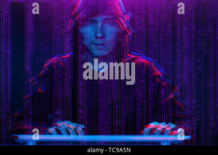 Hacker working with computer in dark room with digital interface around. Image with glitch effect. Stock Photo