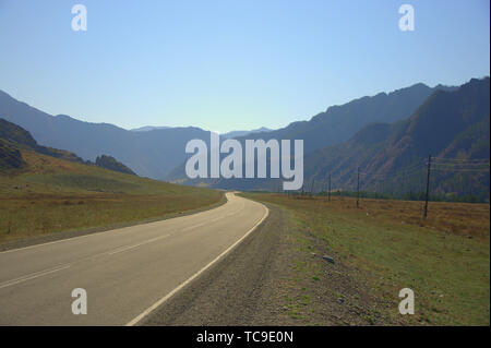 Asphalt road loop between the mountains goes beyond the horizon. Altai, Siberia, Russia. Stock Photo