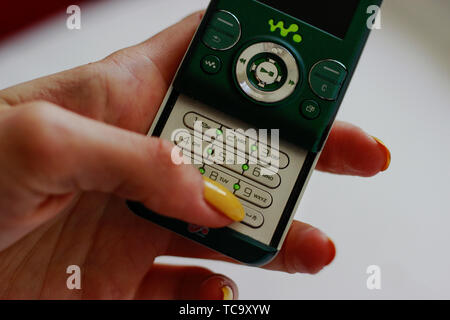 Woman is holding a green Sony Ericsson W580i Walkman released August 2007, Wales, United Kingdom. Mobile phone with buttons from Virgin Mobile contrac Stock Photo