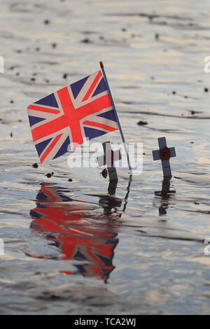 Crosses of remembrance placed alongside a Union flag at dawn on the beach at Arromanches in Normandy, northern France, ahead of a day of events to mark the 75 anniversary of D-Day. Stock Photo