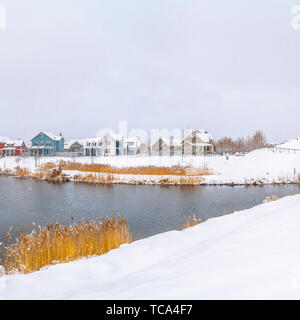 Frame Square Panorama of a silvery lake with distant houses against cloudy sky in winter Stock Photo